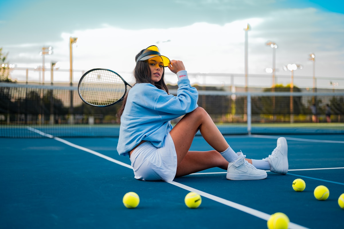 Tennisspielerin sitzt mit Schläger auf dem Tennisplatz